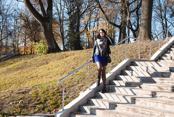 Wall Mural - young girl stands on stairs in city park on autumn day