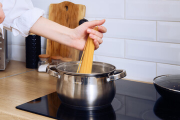 Wall Mural - Closeup view of female hand putting pasta in boiling water