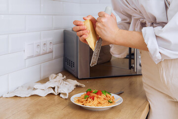 Closeup view of female hands rub cheese on a grater