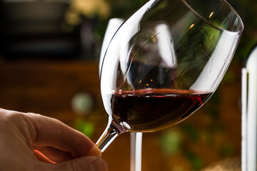 Wine tasting. A glass of red wine on the background of a restaurant table with bottle at an evening dinner or event party.