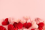 Fototapeta Mapy - Romantic Valentine day background with delicate much of pink and red paper hearts fly on pastel pink background, top view, footer border, copy space. Love backdrop for advertising, text, card.