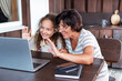 © Oksana Klymenko - Grandmother and granddaughter using laptop for video call to relatives ot friends at kitchen back. Video call event concept.