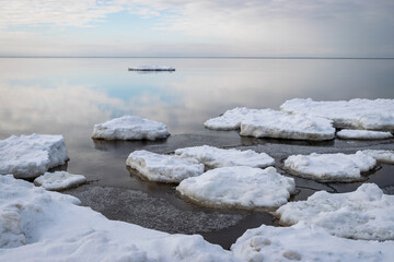 Wall Mural - white pieces of ice floating in the sea, winter landscape from the sea, calm water, sky reflections in the sea