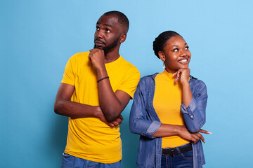 Pensive couple brainstorming ideas and looking sideways, feeling creative. Positive man and woman pondering solution and thinking about clever decision. Curious people in relationship.