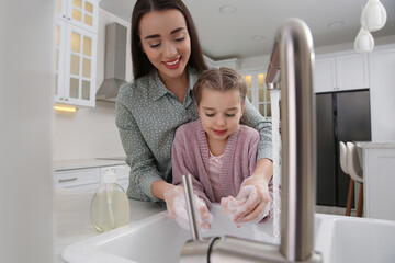 Sticker - Mother and daughter washing hands with liquid soap together in kitchen