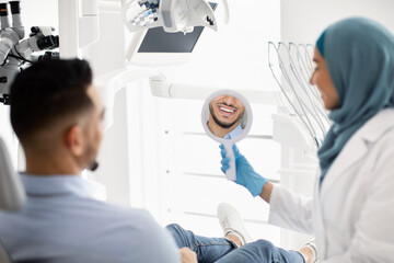 Wall Mural - Arab Male Patient Looking At His Smile After Treatment In Dental Clinic