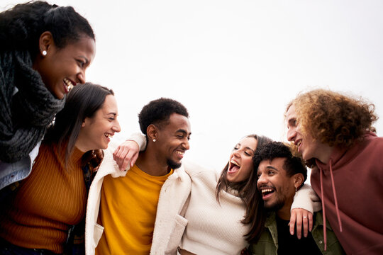 multi-ethnic group of friends hugging and having fun. isolated young smiling people laughing togethe