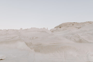 The sandstone white rocks cliffs moonscape of Sarakiniki volcanic beach in Milos Island Greece surrounded by turquoise blue waves and sea at sunset