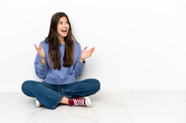 young woman sitting on the floor with surprise facial expression