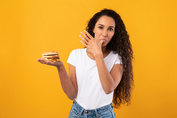 Wall Mural - Happy Latin Lady Holding Burger Licking Finger At Studio