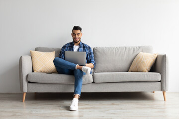 Wall Mural - Portrait of smiling Arab man using laptop at home