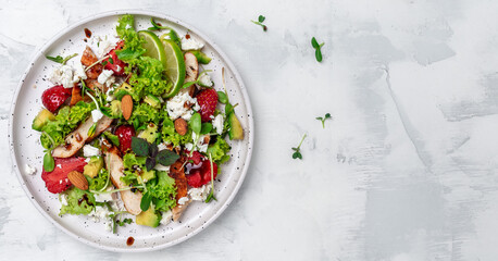 Wall Mural - Fresh salad fruit strawberry with chicken meat avocado, feta cheese, lettuce and nuts balsamic vinegar, Balanced food. Delicious detox diet. Top view
