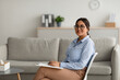 © Prostock-studio - Confident arab female psychologist writing in clipboard, sitting at modern office and smiling at camera, free space