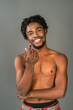 © Svyatoslav Lypynskyy - Shirtless african male model gesturing on camera smiling with arm arms folded. Half naked african american man posing on camera isolated on grey background. Topless african american man