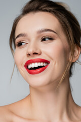 close up portrait of cheerful woman with red lips looking away isolated on grey.