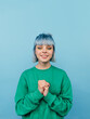 © bodnarphoto - Cute lady in green sweatshirt and colored hair isolated on blue background with smile on face looking at camera.