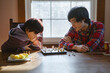 © Cavan Images - A father and son closely study a chess board together in window light