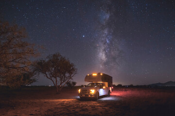 A small pickup RV is on a camping spot under the Milky Way