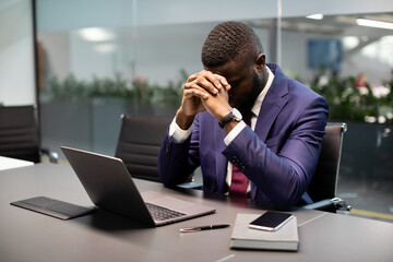 Wall Mural - Frustrated black businessman sitting in front of laptop