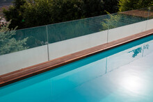 Infinity Swimming Pool With Glassy Safe Fence And Hardwood Decking Edge Overlooking Nature