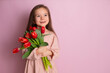 © Анна Брусницына - A little cute girl holding a bouquet of tulips Pink background. Happy women's day. Space for text. Bright Emotions.