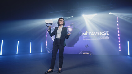 a female speaker in casual clothes in a studio with led screen holding new virtual reality glasses a