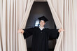 Education, graduation and people concept - happy male student coming out of beige curtains happily on stage