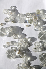 Various transparent beads on white background, illuminated by sunlight and reflectiing light. Flat lay.