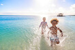 © Brocreative - A Cute diverse boy and little girl running and splashing together in the Caribbean ocean in the late afternoon while on a family vacation