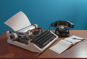 Retro typewriter, checkbook, ink pen and old telephone on the wood table. Blue background