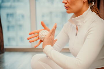 Wall Mural - Athletic slim caucasian woman doing thigh self-massage with a massage ball indoors. Self-isolating massage