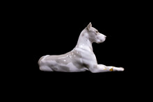 A Dog Of The White Great Dane Breed Is Isolated On A Black Background. Porcelain Figurine