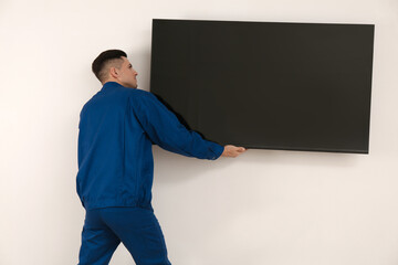 Canvas Print - Professional technician installing modern flat screen TV on wall indoors