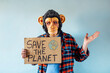 © karrastock - Man with monkey mask showing a sign that says SAVE THE PLANET.