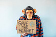 © karrastock - Man with monkey mask showing a sign that says SAVE THE PLANET.