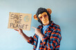 © karrastock - Man with monkey mask showing a sign that says SAVE THE PLANET.