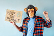 © karrastock - Man with monkey mask showing a sign that says SAVE THE PLANET.