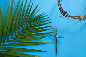 Wall Mural - Crown of thorns, cross and branch of palm leaves on a blue background