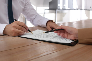 Sticker - Businesspeople working with contract at wooden table indoors, closeup