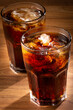 © WS Studio - Coke glasses with ice cubes on wooden table.