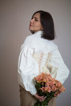  Girl In A White Shirt And Beige Corset Holds Flowers In Her Hands
