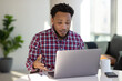 © blvdone - Black man at home remote working on laptop computer talking with colleague