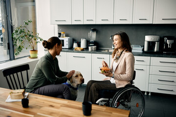 Wall Mural - Happy handicapped businesswoman and her female coworker enjoy with assistance dog during lunch break in the office.