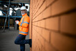 Portrait of factory worker in safety equipment standing by brick wall in factory.