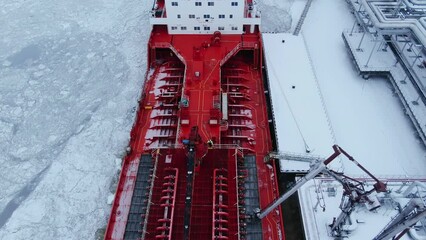 Wall Mural - Oil shipment on big red tanker from terminal pumping system on water covered with thick layer of broken ice in frosty winter aerial view