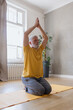 © MyJuly - senior yoga, a man with gray hair meditates and does breathing exercises. sports fitness and physical exercises for the elderly. a fifty-year-old European man holds his hands in namaste in a yellow T