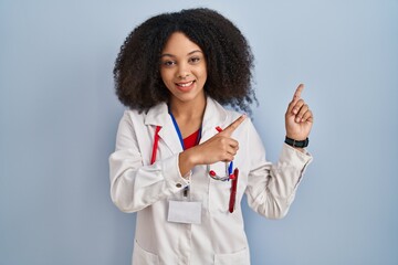 Poster - Young african american woman wearing doctor uniform and stethoscope smiling and looking at the camera pointing with two hands and fingers to the side.