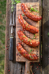 Wall Mural - Hot roasted sausages on wooden plate in garden.