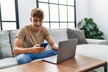 Sticker - Young caucasian man smiling confident using laptop and smartphone at home