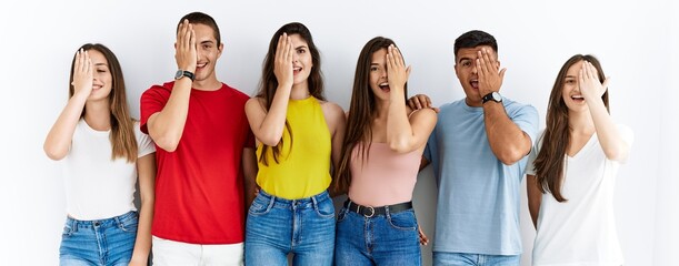 Canvas Print - Group of people wearing casual clothes standing over isolated background covering one eye with hand, confident smile on face and surprise emotion.